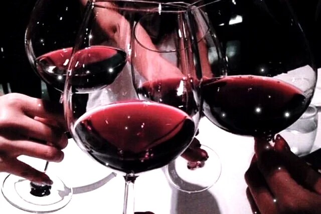 Friends raising glasses of red wine across a dinner table