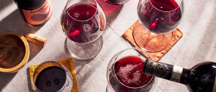 Red wine poured into glasses on a sunlit marble table